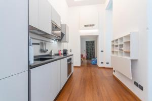 cocina con armarios blancos y suelo de madera en Elegant Home with Sauna in Turin by Wonderful Italy, en Turín