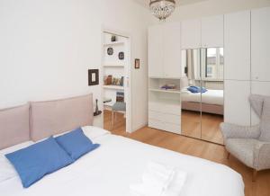 a white bedroom with a bed and a chair at Luma Apartment Navigli: Cozy and Romantic Getaway in Milan