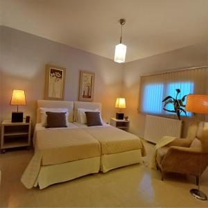 a bedroom with a large bed and a chair at Mythos luxury apartments in Corfu