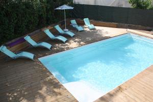 a swimming pool with lounge chairs and an umbrella at Gîte La Villa Gaïa in Nérac
