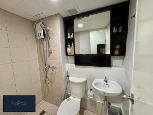 a bathroom with a toilet and a sink and a mirror at CozyVilla at Pine Suites Tagaytay 2BR or Studio with FREE PARKING in Tagaytay