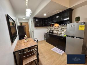 a kitchen with a table and a refrigerator at CozyVilla at Pine Suites Tagaytay 2BR or Studio with FREE PARKING in Tagaytay