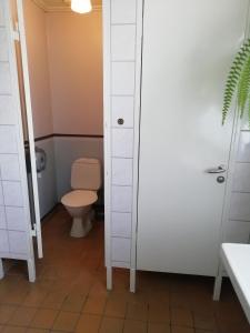 La salle de bains est pourvue de toilettes et d'une porte blanche. dans l'établissement Moshults Vandrarhem, à Moshultamåla