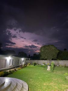 einen Hinterhof in der Nacht mit Haus und Rasen in der Unterkunft Cumberland Guest Lodge in Bulawayo