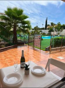 a white table with two glasses and a bottle of wine at Lovely apartment Taidia in Maspalomas