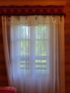 una ventana con cortinas blancas en una habitación en B&B Cristallo, en Cortina dʼAmpezzo