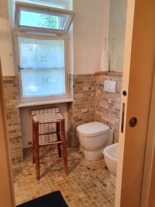 a bathroom with a toilet and a window and a stool at B&B Cristallo in Cortina dʼAmpezzo