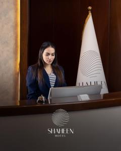 a woman sitting in front of a desk with a laptop at Shaheen Hotel Baghdad in Baghdād