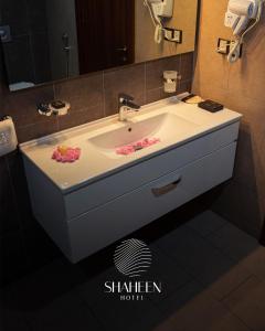 a bathroom sink with pink flowers on it at Shaheen Hotel Baghdad in Baghdad