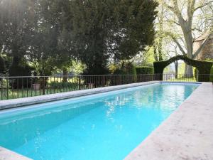 a blue swimming pool with a fence and trees at Domaine La Bonne Etoile in Beausemblant
