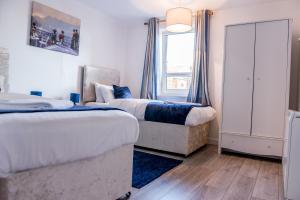 um quarto com 2 camas e uma janela em Bomaquarters COSY AND LUXURIOUS 2 BED VILLIERS HOUSE em Coventry