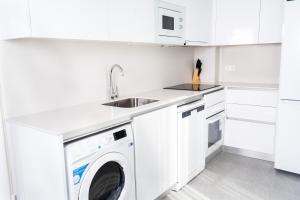 uma cozinha branca com uma máquina de lavar roupa e um lavatório em Apartamentos Turísticos Plaza del Rey em Cartagena