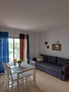 a living room with a table and a blue couch at COMODORO- RAVEL in Los Cristianos