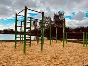 un parque de juegos vacío en la arena cerca del agua en Ferienwohnung Meerblick, en Ihlow