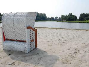 una silla blanca sentada en la playa junto al agua en Ferienwohnung Meerblick, en Ihlow