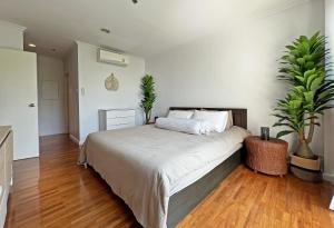 una camera da letto con un grande letto con due piante in vaso di 2BR Beachfront Condo in central HuaHin, Baan Saen Ploen a Hua Hin