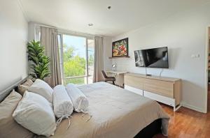 a bedroom with a bed with a television and a desk at 2BR Beachfront Condo in central HuaHin, Baan Saen Ploen in Hua Hin