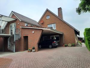 a brick house with a car parked in the driveway at FeWo Bohlen-Wieke in Ihlow