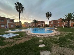 una piscina en un patio con palmeras en OLIVA NOVA GOLF BEACH & RESORT Club Sevilla VI 3A, en Oliva