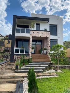a large white house with stairs in a yard at Furnished House at Kibagabaga in Kigali