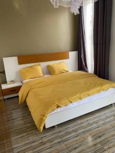 a bedroom with a bed with a yellow blanket at Furnished House at Kibagabaga in Kigali