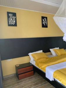 a bedroom with two beds and two pictures on the wall at Furnished House at Kibagabaga in Kigali