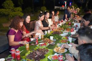 a group of people sitting around a long table full of food at VIOLET VILLA in Hòa Bình