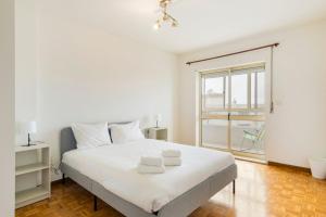 a white bedroom with a large bed and a window at GuestReady - Unwind in Ryan's Place in Braga