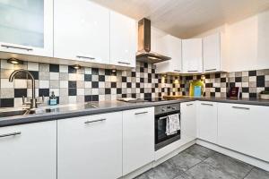 uma cozinha com armários brancos e azulejos pretos e brancos em Kensington 2 BEDROOM HOUSE-BIG living area and kitchen-Harrods-National History Museum-Hyde Park-Near 2 underground lines em Londres