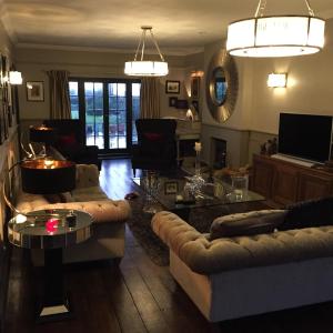 uma sala de estar com dois sofás e uma televisão em Ingram House with Hot Tub em Hurst Green