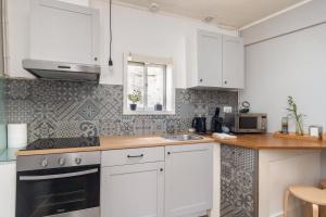 uma cozinha com armários brancos e um lavatório em GuestReady - Guimarães Urban Retreat em Guimarães