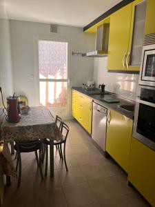 a kitchen with yellow cabinets and a table with chairs at La oliva in Cáceres +3 photos