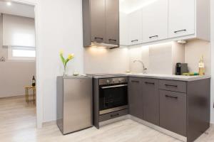 a kitchen with stainless steel appliances and white cabinets at Brand New flat near Lycabettus Hill by Luckeys in Athens