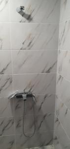 a shower in a bathroom with white marble tiles at Нощувки вип класа in Razgrad