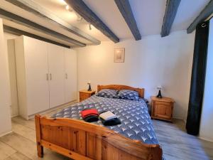 ein Schlafzimmer mit einem Holzbett in einem Zimmer in der Unterkunft Duplex de l'Arbre de la Liberté in Guebwiller