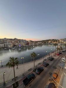 a city with cars parked next to a body of water at B&S Accommodation Seafront Duplex Penthouse in Marsaskala