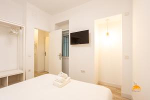 1 dormitorio blanco con 1 cama y TV en Bajo el Falla by Cadiz Time, en Cádiz