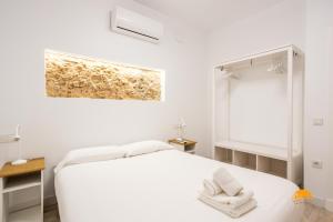 Un dormitorio blanco con una cama con toallas. en Bajo el Falla by Cadiz Time, en Cádiz