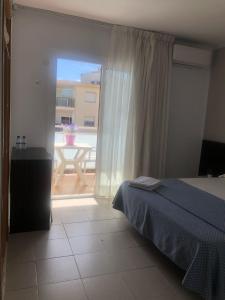 1 dormitorio con cama y vistas a un balcón en Hostal Tahiti RS, en Salou