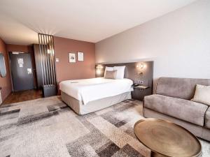 a hotel room with a bed and a couch at Mercure Bordeaux Lac in Bordeaux