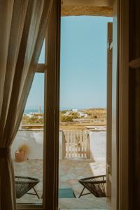 una porta aperta su un patio con vista sull'oceano di Enea by TinosHost a Città di Tinos