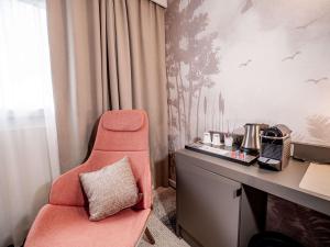 a room with a desk with a chair next to a desk at Mercure Bordeaux Lac in Bordeaux