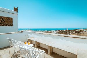 a balcony with a table and chairs and a view of the ocean at Enea by TinosHost in Tinos Town