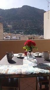 a table with two cups and a vase with flowers on it at Sandro Apartment in Castellammare del Golfo