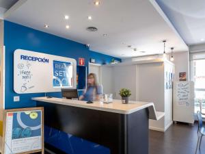 a woman sitting at a reception desk in a room at Ibis Budget Madrid Centro Las Ventas in Madrid