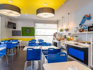 un ristorante con sedie blu, tavoli e soffitti gialli di Ibis Budget Madrid Centro Las Ventas a Madrid