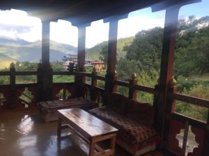 a porch with a couch and a table and a view at Mendrelgang Homestay in Punākha