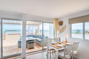 Un comedor y una sala de estar con mesa y sillas. en Beachfront Penthouse, en Colònia De Sant Jordi