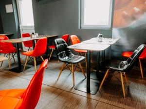 a dining room with tables and red chairs at Ibis Sofia Airport Hotel in Sofia