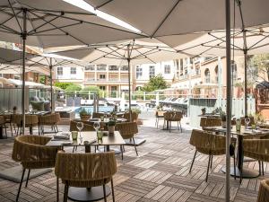 un restaurante con mesas, sillas y sombrillas en Grand Hôtel Roi René Aix en Provence Centre - MGallery, en Aix-en-Provence